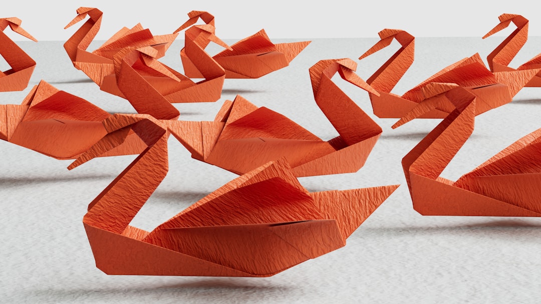 Red paper swans floating above a texture. by Best 3D Printer a group of orange origami swans sitting on top of a table